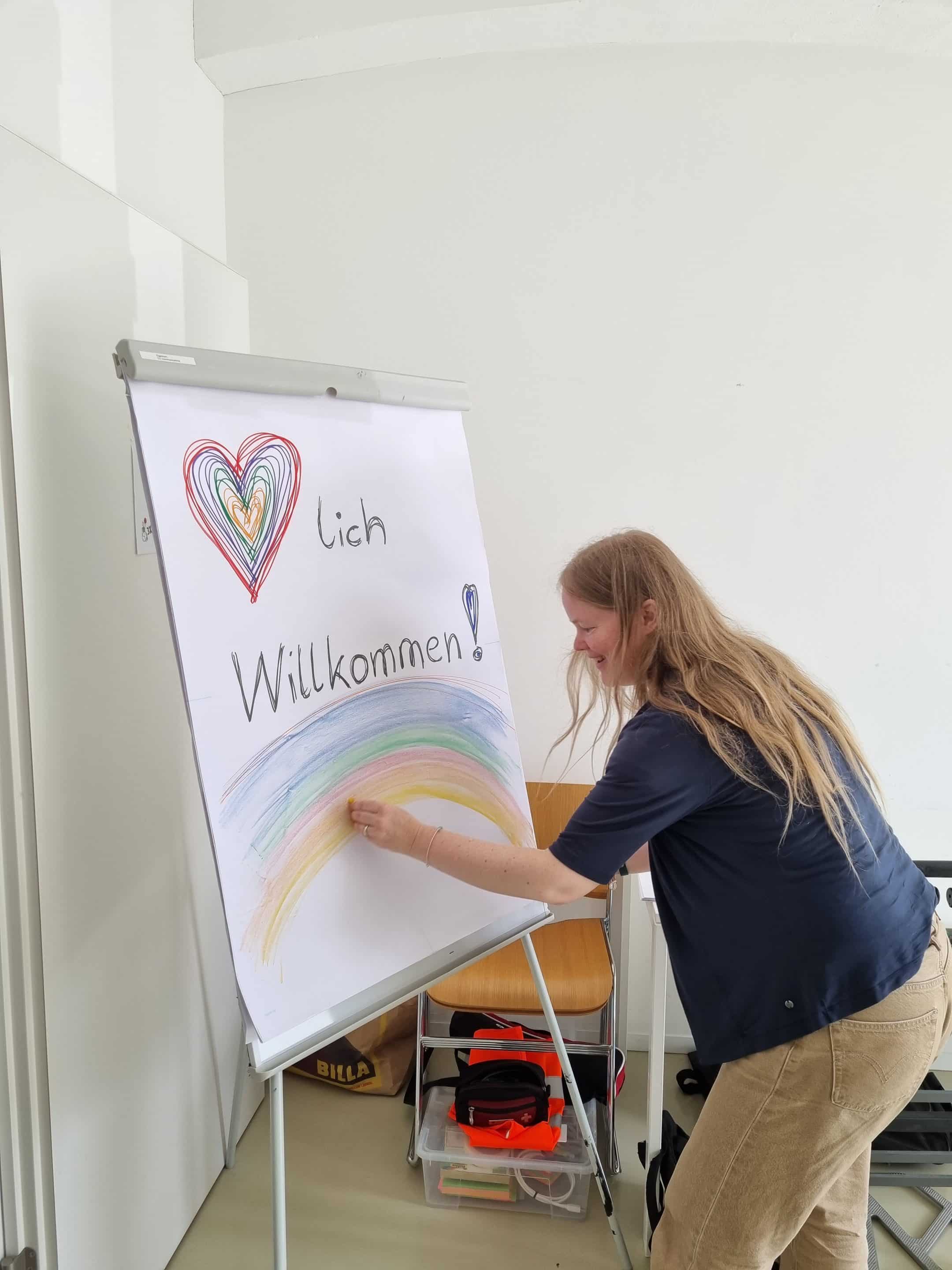 Ingrid Otepka zeichnet als Willkommensgruß einen Regenbogen auf das Flipchart. 